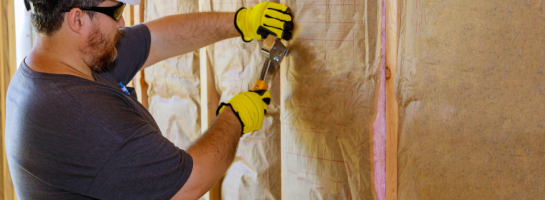 Man Installing Thermal Insulation Layer under the Wall Using Mineral Wool