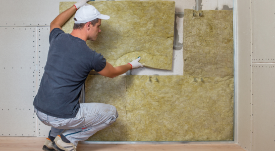 Worker Insulating a Room Wall with Mineral Rock Wool Thermal Insulation.